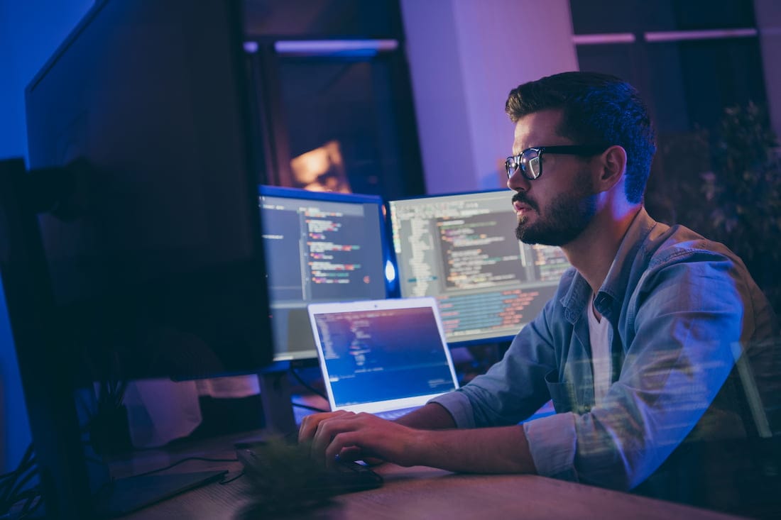 Developer working hard and using multiple monitors to develop a website