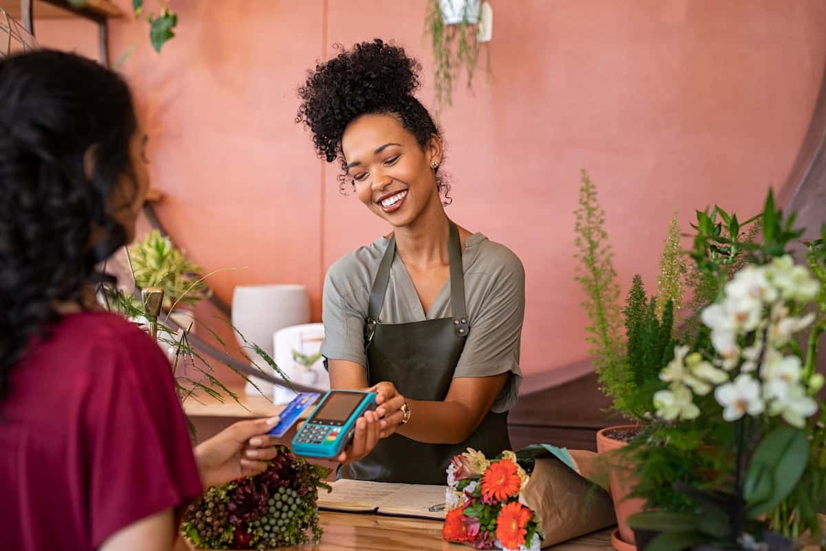Smiling business owner taking payment from a customer in her flower shop
